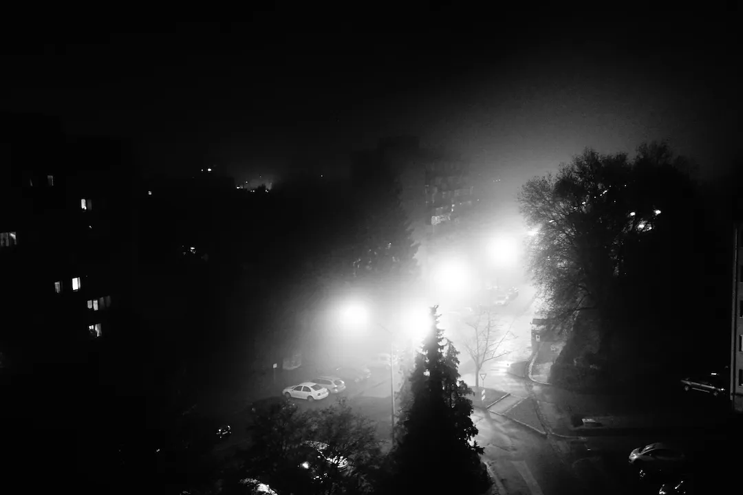 Foggy street at night, lit by street lamps, in black and white